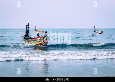 SERREKUNDA, GAMBIA - 21. NOVEMBER 2019: Szene mit Männern und Frauen, die Fische von den Booten zum Strand auf Serrekunda, Gambia, Westafrika, tragen. Stockfoto