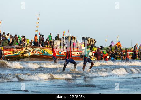 TANJI, GAMBIA - 21. NOVEMBER 2019: Menschen, die Fische von den Booten zum Strand auf Tanji, Gambia, Westafrika, tragen. Stockfoto