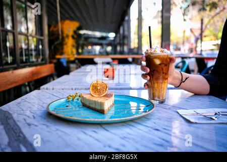 Frappe-Kaffee mit Zitronenkäsekuchen auf Marmortisch Stockfoto