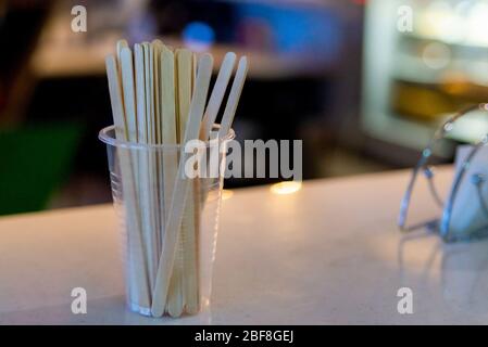 Holzstäbchen in Plastikbecher zum Rühren von Zucker in Kaffee in der Cafeteria. Stockfoto