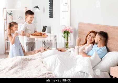 Kleine Kinder bringen ihre Eltern Frühstück im Bett Stockfoto