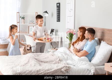 Kleine Kinder bringen ihre Eltern Frühstück im Bett Stockfoto