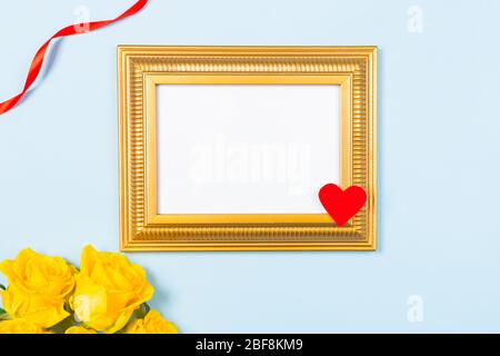 Golden Frame leere leere Bild und gelbe Rosen auf hellblauem Hintergrund. Kopieren Sie Speicherplatz freien Speicherplatz für Text. Konzept der Urlaubskarte. Mock-up. Gruß Stockfoto