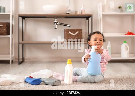 Kleines afroamerikanisches Baby, das zuhause mit dem Waschen von Flüssigkeiten spielt. Kind in Gefahr Stockfoto