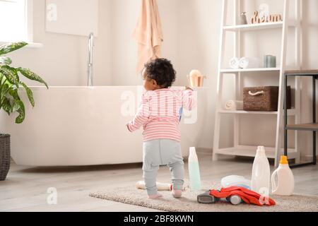 Kleines afroamerikanisches Baby, das zuhause mit dem Waschen von Flüssigkeiten spielt. Kind in Gefahr Stockfoto