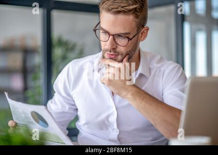 Junger schöner Mann in weißem Hemd sieht konzentriert aus Stockfoto