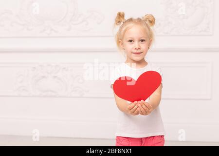 Kleine liebenswert Mädchen bereitet sich darauf vor, ihr Herz-förmigen Auto zu jemandem zu geben. Stockfoto