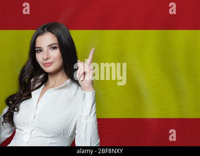 Frau zeigt auf spanischen Flagge Hintergrund. Ausbildung oder Geschäftskonzept Stockfoto