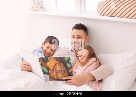 Vater und seine kleinen Kinder lesen Schlafensgeschichte zu Hause Stockfoto