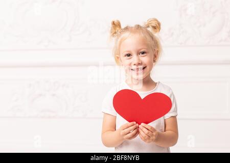 Kleine liebenswert Mädchen bereitet sich darauf vor, ihr Herz-förmigen Auto zu jemandem zu geben. Stockfoto