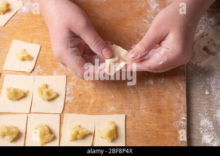 Weibliche Hände Formen Knödel aus Teig mit Kartoffeln. Kochen zu Hause. Stockfoto