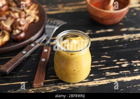 Glas mit leckerer Honig-Senf-Sauce auf Holztisch Stockfoto