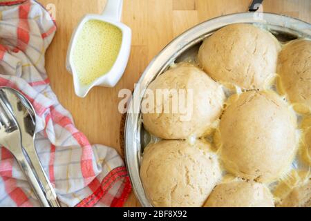 Traditionelle frische bayerische Hefeknödel, vegane Version, serviert mit Vanillesauce in einer Pfanne Stockfoto