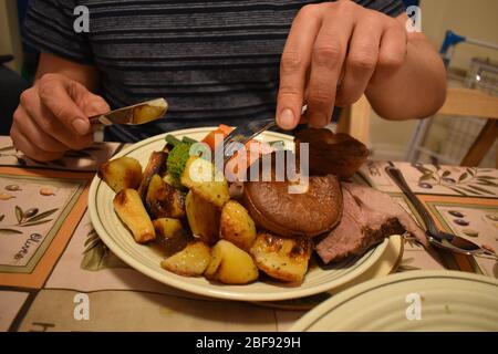 Mann, der am Sonntag Lammbraten gegessen hat. Teller voller Kartoffeln Lauch Karotten Brokkoli Yorkshire Pudding geschnitzte Fleisch grüne Bohnen. Traditionelle britische Küche Stockfoto