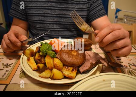 Traditionelle britische Küche hausgemachte Sonntag Lamm Braten Abendessen mit Soße Teller voller Kartoffeln Lauch Karotten Brokkoli Yorkshire Pudding geschnitzten Fleischbohnen Stockfoto