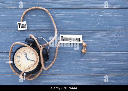 Wecker mit Seil und Text ZEITMANAGEMENT auf Holzhintergrund Stockfoto