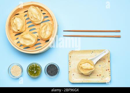 Dampfgarer mit orientalischen Knödeln und Sauce auf farbigem Hintergrund Stockfoto