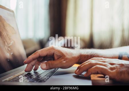 Ein Mann, der mit einem Laptop zu Hause einkaufen geht. Männliche Hand tippen auf Laptop-Tastatur im Büro. Geschäftsmann, Student, Arbeit von zu Hause, Abstand educati Stockfoto