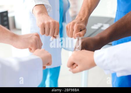 Gruppe von Ärzten, die sich in der Klinik zusammenfügen. Einheitlichkeit Stockfoto