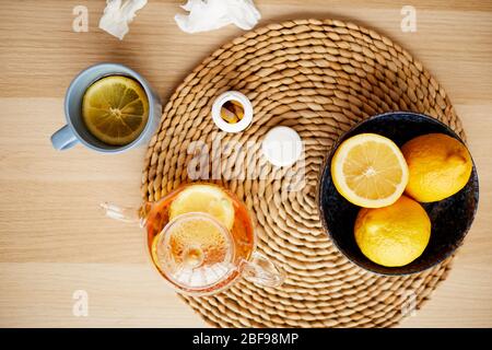 Blick aus dem hohen Winkel auf heißen Tee mit Zitrone und Flasche mit Pillen auf dem Tisch Stockfoto