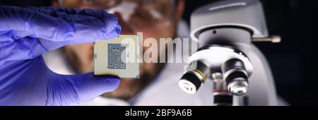 Maskierter Mann untersucht einen Mikrokreis nahe Mikroskop Stockfoto