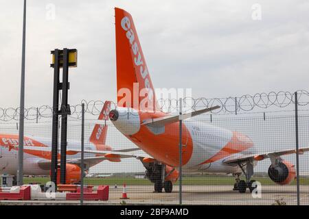 Southend-on-Sea, Großbritannien. April 2020. Zwei EasyJet-Flugzeuge parkten auf dem Rollfeld am London Southend Airport in Essex, Großbritannien. Die Flugzeuge tragen die charakteristische orange-weiße Lackierung der Fluggesellschaft und befinden sich hinter einem Sicherheitszaun mit Stacheldraht. Der bewölkte Himmel und die Flughafeninfrastruktur, darunter rote und weiße Barrieren und ein schwarz-gelber Pfosten, deuten auf eingeschränkten Zugang und einen eingeschränkten betrieblichen Kontext hin. Flugzeuge sitzen auf der Start- und Landebahn des Flughafens Southend, nachdem europäische Staaten und große europäische Fluggesellschaften Maßnahmen ergriffen haben, um auf die COVID-19-Pandemie zu reagieren. Penelope Barritt/Alamy Live News Stockfoto