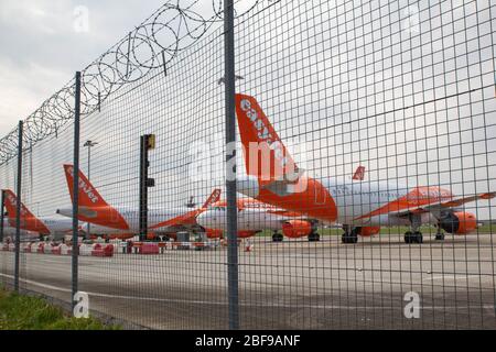 Southend-on-Sea, Großbritannien. April 2020. Mehrere EasyJet-Flugzeuge in orange und weißer Lackierung parken auf dem Rollfeld am Flughafen London Southend, von außen gesehen. Der hohe Metallzaun mit Stacheldraht betont eingeschränkten Zugang und Sicherheitsprotokolle am Flughafen. Nach Maßnahmen, die von europäischen Staaten und großen europäischen Fluggesellschaften als Reaktion auf die COVID-19-Pandemie ergriffen wurden, sitzen die easyJet-Flugzeuge auf der Start- und Landebahn des Flughafens Southend. Penelope Barritt/Alamy Live News Stockfoto
