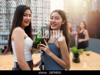 Eine Gruppe junger asiatischer Frauenfreunde hat einen glücklichen Moment, um in der Diskothek Tanzparty mit einer Flasche Bier in der Hand zu feiern. Stockfoto