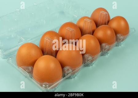 Eier in einer Plastikverpackung mit isoliertem türkisfarbenem Hintergrund. Stockfoto