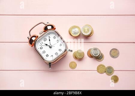 Wecker und Münzen auf Holztisch. Konzept des Zeitmanagements Stockfoto