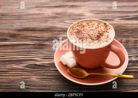 Tasse leckeren Cappuccino auf Holzhintergrund Stockfoto