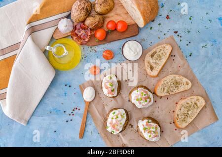 Leckere gebackene Kartoffel mit saurer Sahne auf Brot auf farbigen Hintergrund Stockfoto