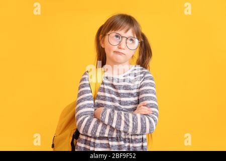 Gelangweilt kleine Schulmädchen auf farbigen Hintergrund Stockfoto