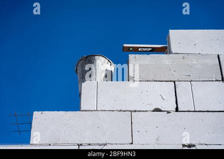 Baue eine Wand aus Schaumstoffblöcken. Neue Wand aus weißem Schaum blockiert gegen den blauen Himmel Stockfoto