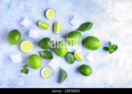 Frische Limetten und Eiswürfel auf farbigem Hintergrund Stockfoto