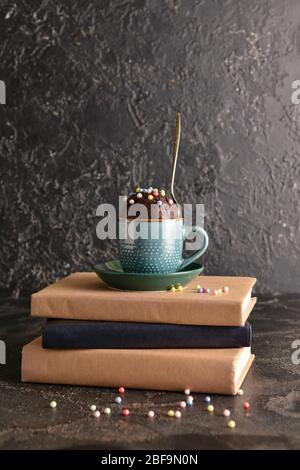 Schokoladenbecher Kuchen mit Büchern auf dunklem Hintergrund Stockfoto