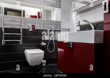 Interieur eines modernen Badezimmers mit Waschbecken und Toilette in grau-roten Farben Stockfoto