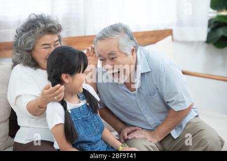 Glücklich asiatisch ältester glücklich Großvater Kopf berühren Enkeltochter Kopf während auf Sofa sitzen und Freizeit zusammen zu Hause haben. Stockfoto