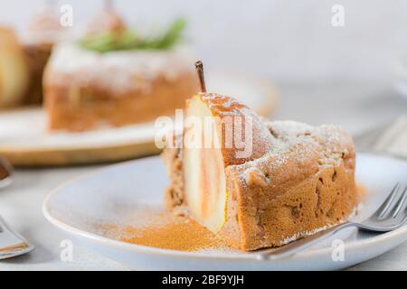 Köstliche Tortenscheibe mit Birne, Ingwer und Zimt auf einem Teller in einer dunklen Küchentheke. Stockfoto