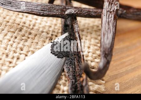 Messer und aromatische Vanillestäbchen auf Holzhintergrund, Nahaufnahme Stockfoto