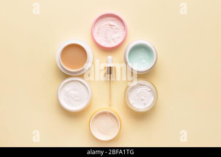 Gläser Creme und Tropf auf farbigen Hintergrund Stockfoto