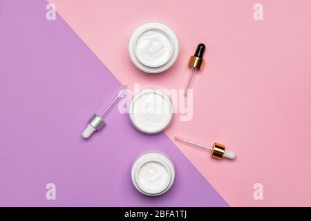 Gläser von Sahne und Tropfer auf farbigen Hintergrund Stockfoto