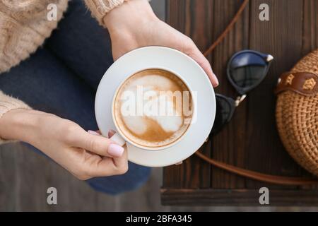 Frau trinkt leckeren Cappuccino im Café Stockfoto