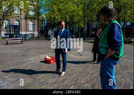 Den Haag, Niederlande. April 2020. Hugo De Jonge, stellvertretender Ministerpräsident und Gesundheitsminister, Wohlfahrt und Sport im dritten Kabinett Rutte spricht mit einem XR-Aktivisten während der Sperrung des Coronavirus (COVID-19).der Platz, auf dem sich das Repräsentantenhaus der Niederlande in Den Haag befindet, war mit mehr als Tausenden von Schuhen von den Extinction Rebellion Aktivisten gefüllt. Diese Woche hätte die Klima-AktivistInnen-Gruppe XR während der Frühjahrsrebellion protestiert, aber wegen der aktuellen Situation konnte das nicht möglich sein, so dass sie die Schuhe als symbolische Aktion verließen. Credi Stockfoto