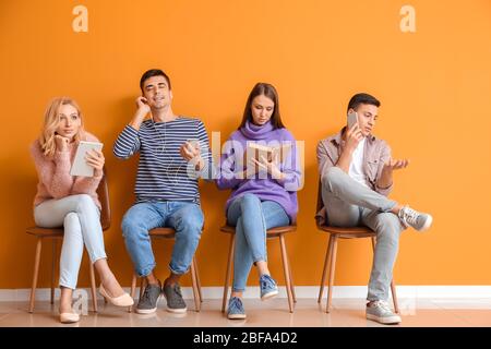 Junge Leute warten in der Schlange in der Nähe von Farbwand Stockfoto