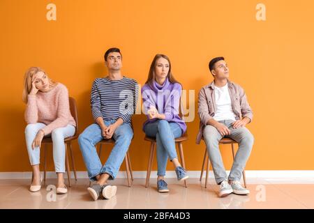 Junge Leute warten in der Schlange in der Nähe von Farbwand Stockfoto