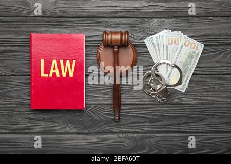 Richtergabel, Buch, Geld und Handschellen auf Holzhintergrund Stockfoto