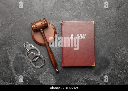 Richtergabel, Buch und Handschellen auf grauem Hintergrund Stockfoto