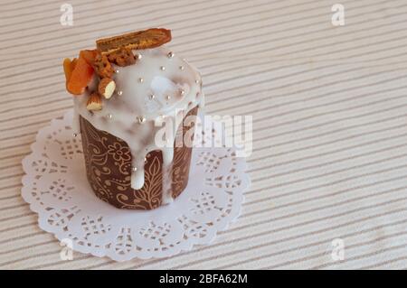 Orthodox Ostern kulich. Stilvoll leckerer Kuchen auf der weißen Serviette, verziert mit getrockneten Bananen, Orangenaprikosen, Mandeln und kleinem, eleganten Zuckersilber Stockfoto