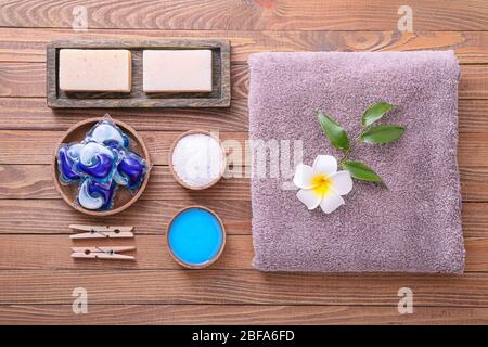 Zusammensetzung mit Handtuch und Waschmittel auf Holzhintergrund Stockfoto